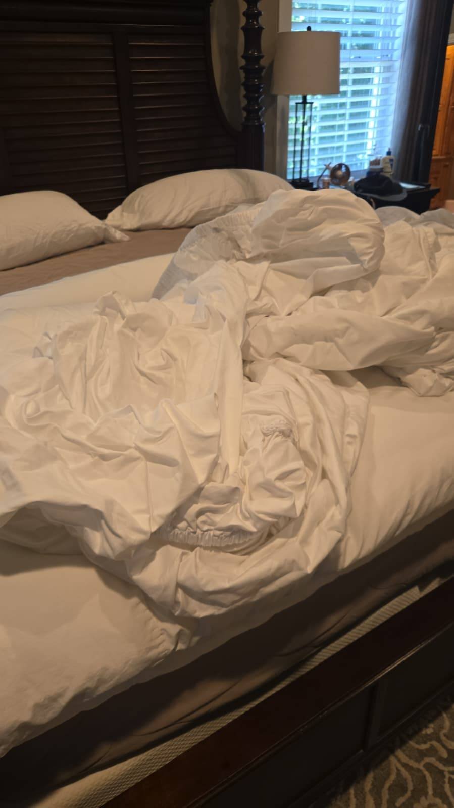 Unmade bed with sheets and blankets scattered before cleaning