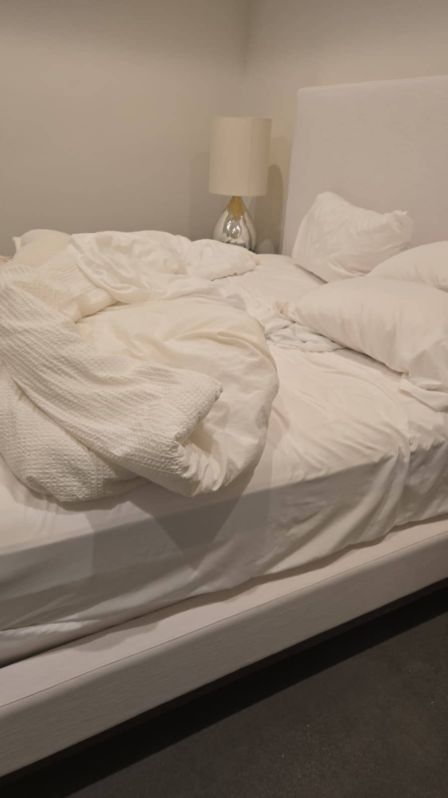 Freshly made bed with crisp white linens after professional cleaning