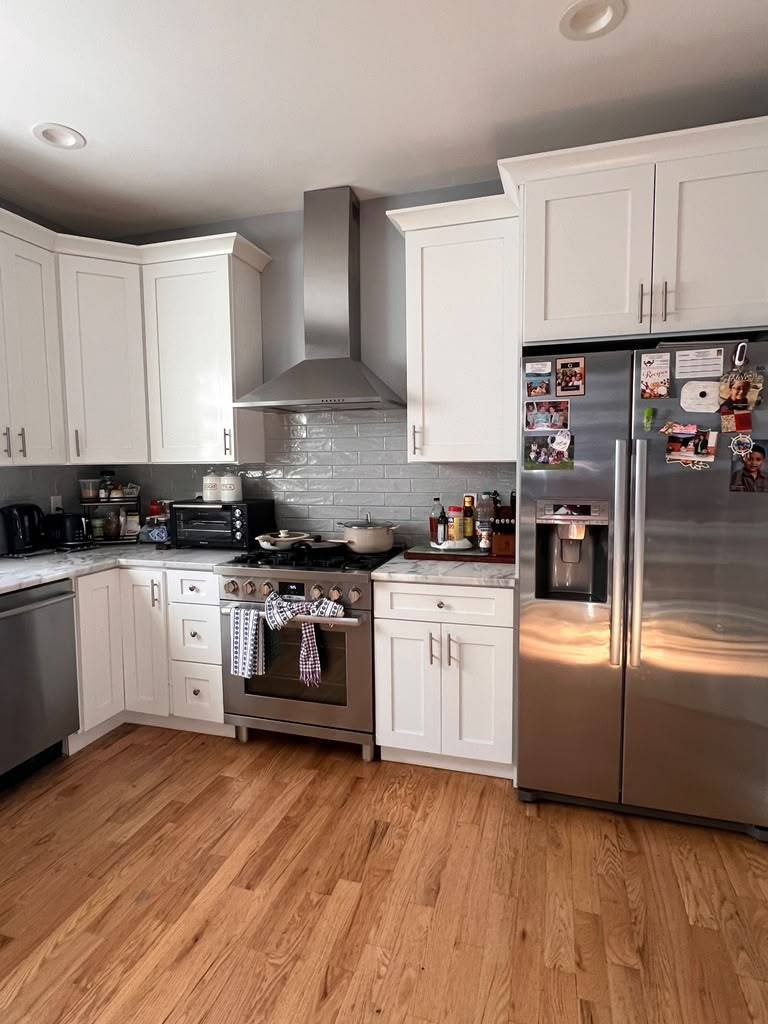 Clean white kitchen with marble counters and stainless appliances after cleaning