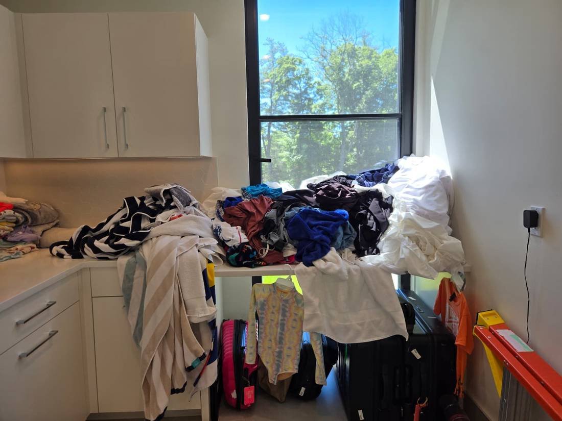Laundry area with clothes piled on counters before organization